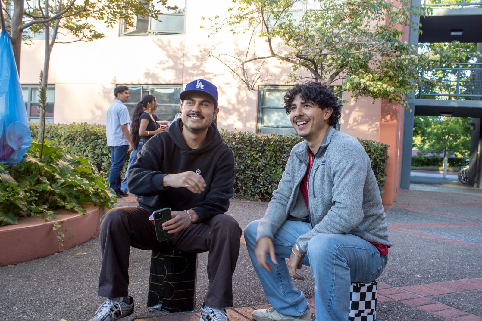 Two friends seated on Street Seats, laughing together outside a campus courtyard