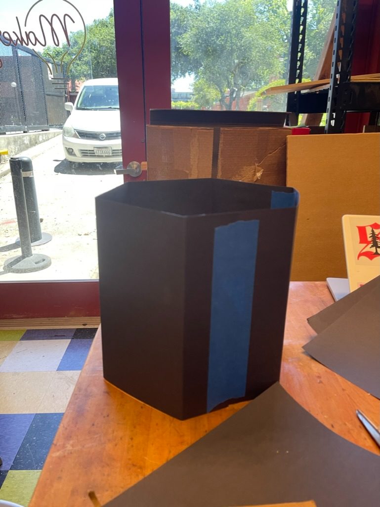 Black foam mini prototype with blue tape, sitting on a workbench