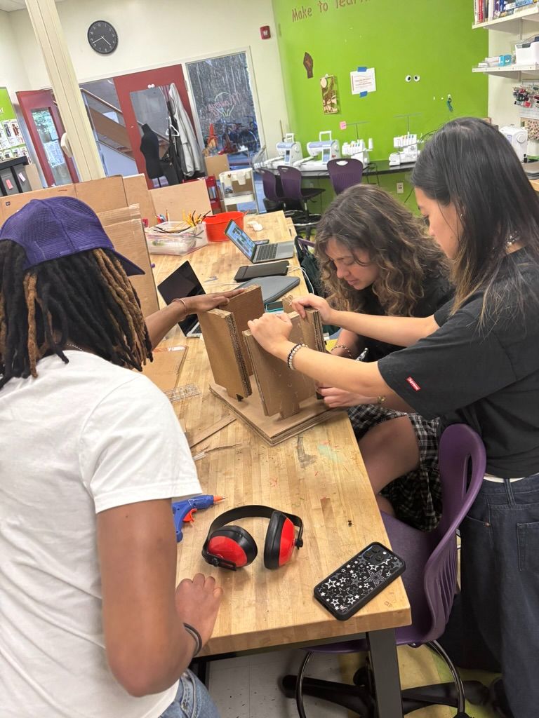 Team assembling the cardboard hexagonal frame around a workbench