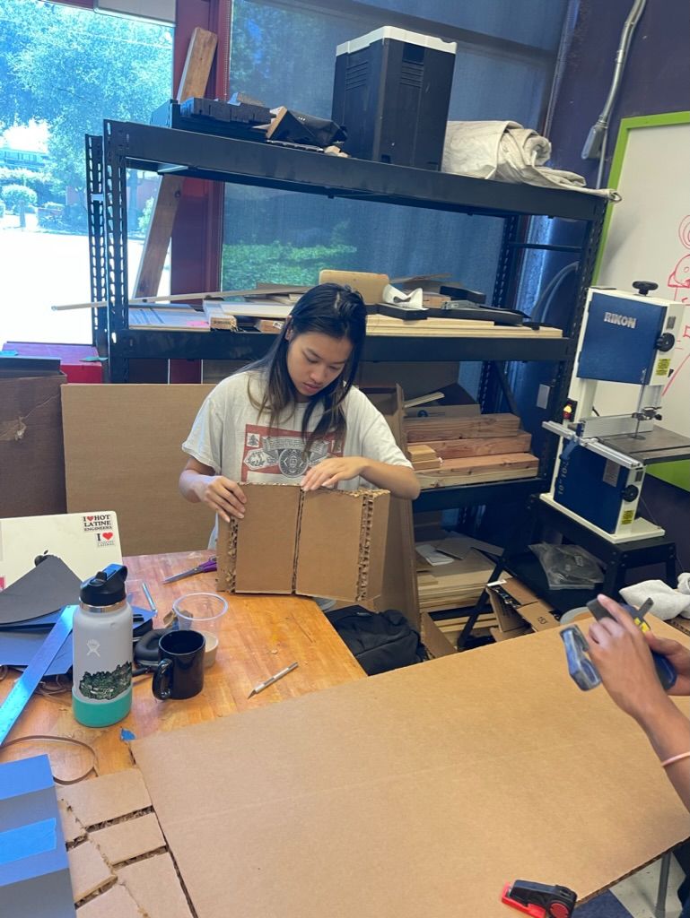 Student scoring and folding a sheet of corrugated cardboard