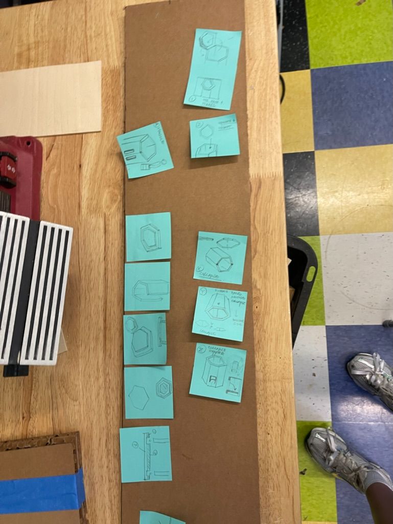 Hexagonal stool sketches laid out on Post-its over a sheet of cardboard